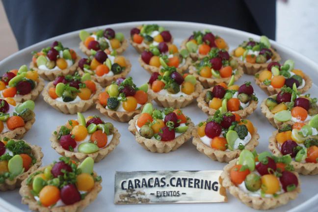 A beautifully arranged platter of vibrant vegan pastries and fresh fruit at an outdoor catering event
