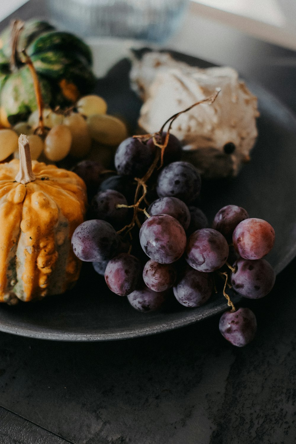 a plate of food with grapes, cheese, and a pumpkin