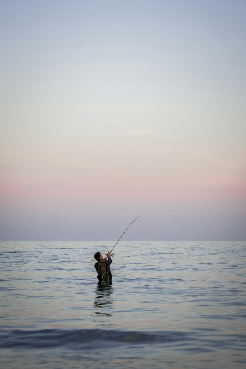 a man standing in the water holding a fishing rod