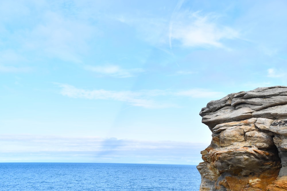 Un homme debout au sommet d’une falaise au bord de l’océan