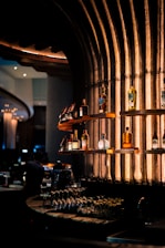 Interior of a modern bar with neatly arranged bottles and glasses on shelves.