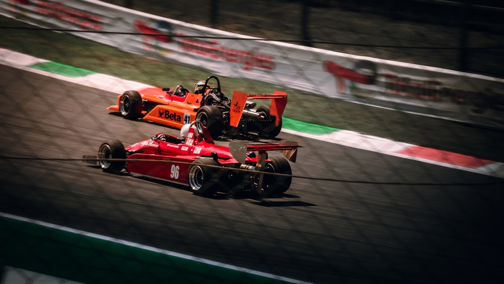 a couple of racing cars driving down a race track