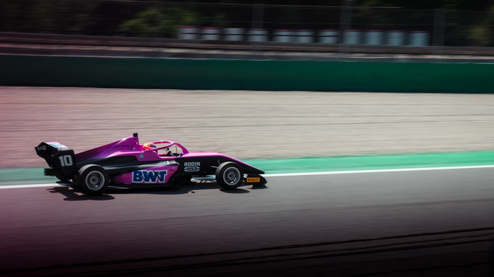 a pink race car driving down a race track
