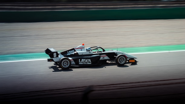 Elegant black and white photo of a motorsports car mid-race, printed on fine art paper with subtle metallic sheen.