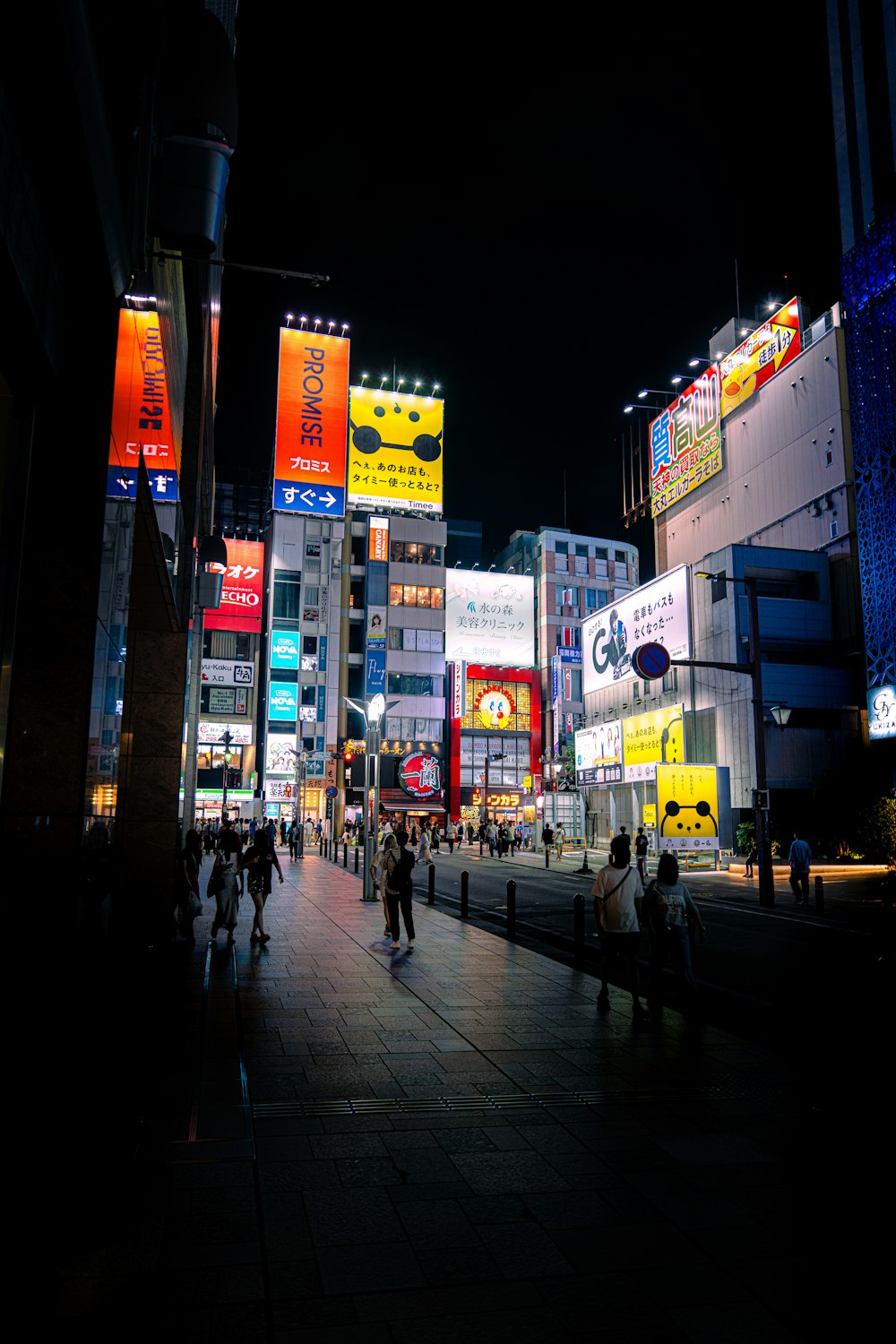 a group of people walking down a street next to tall buildings