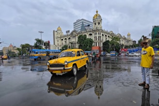 A sleek blue and orange taxi parked near a popular local landmark in Bharuch