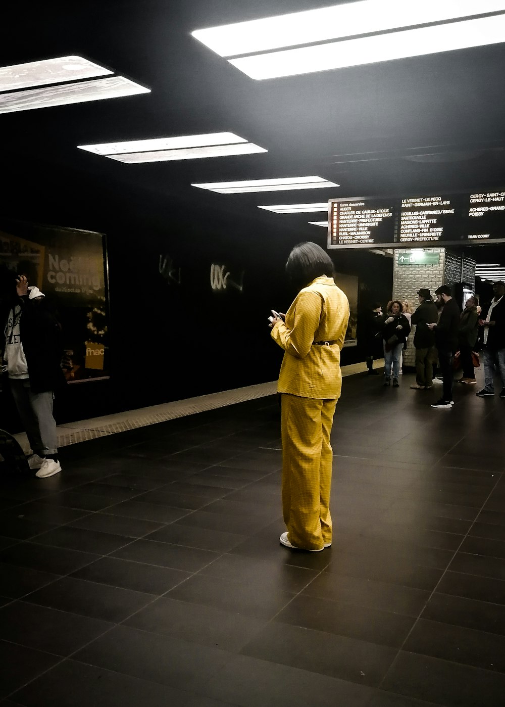 a person in a yellow outfit standing in a subway station