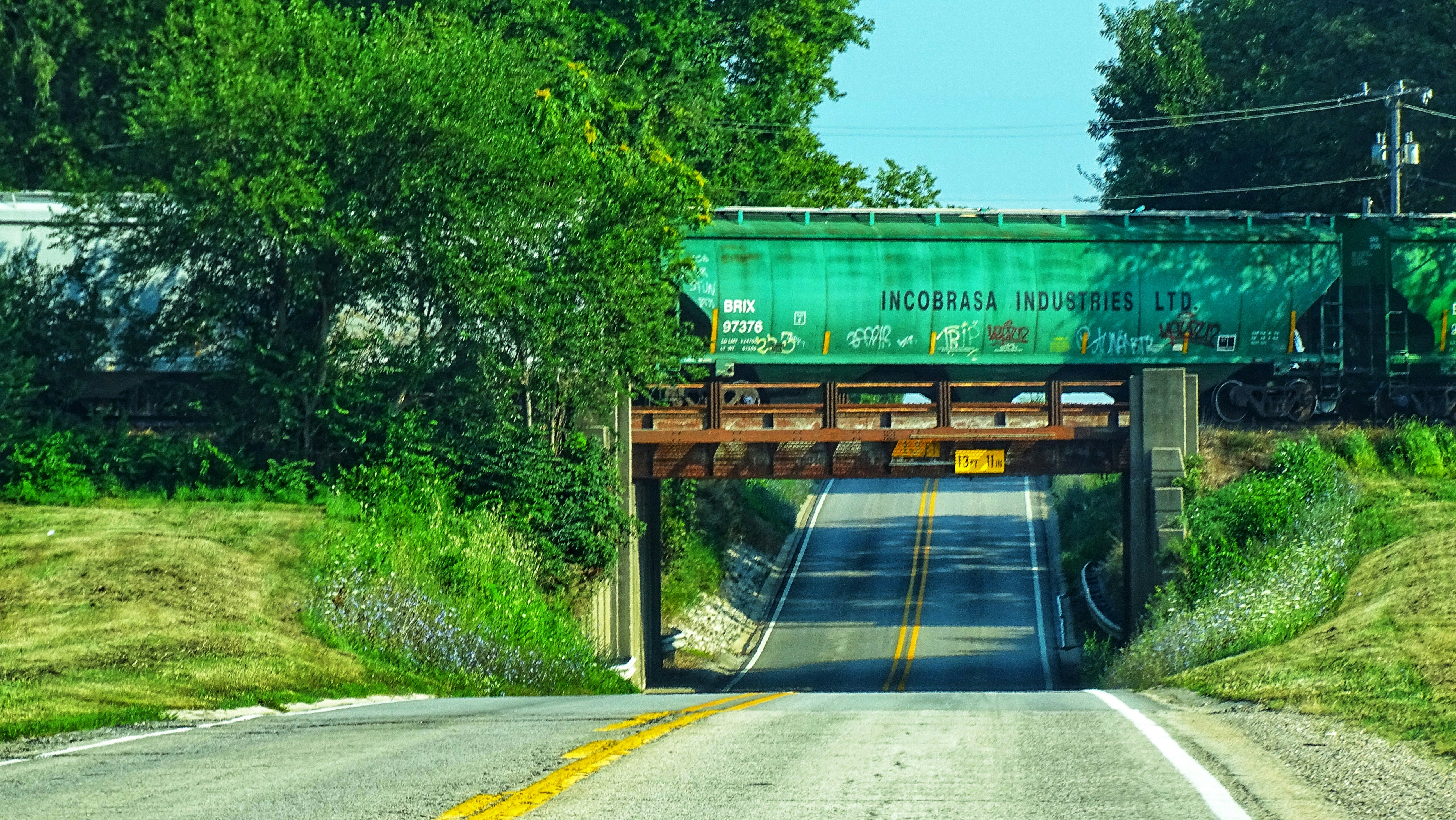a green train traveling over a bridge over a road