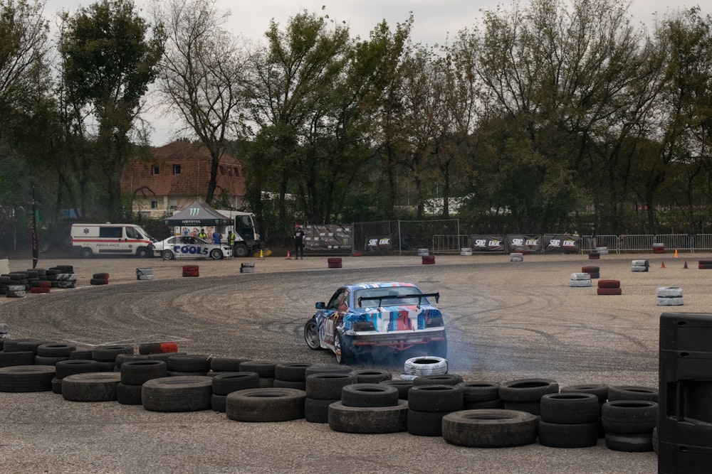 a car driving around a track with tires around it