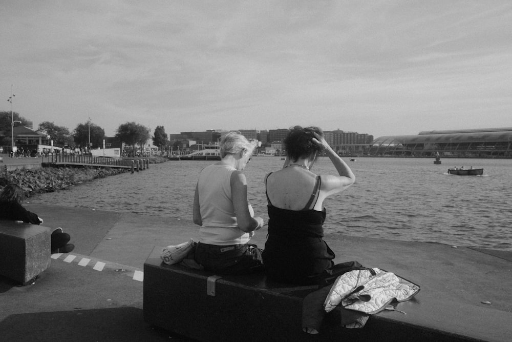 a man and a woman sitting on a bench looking at the water