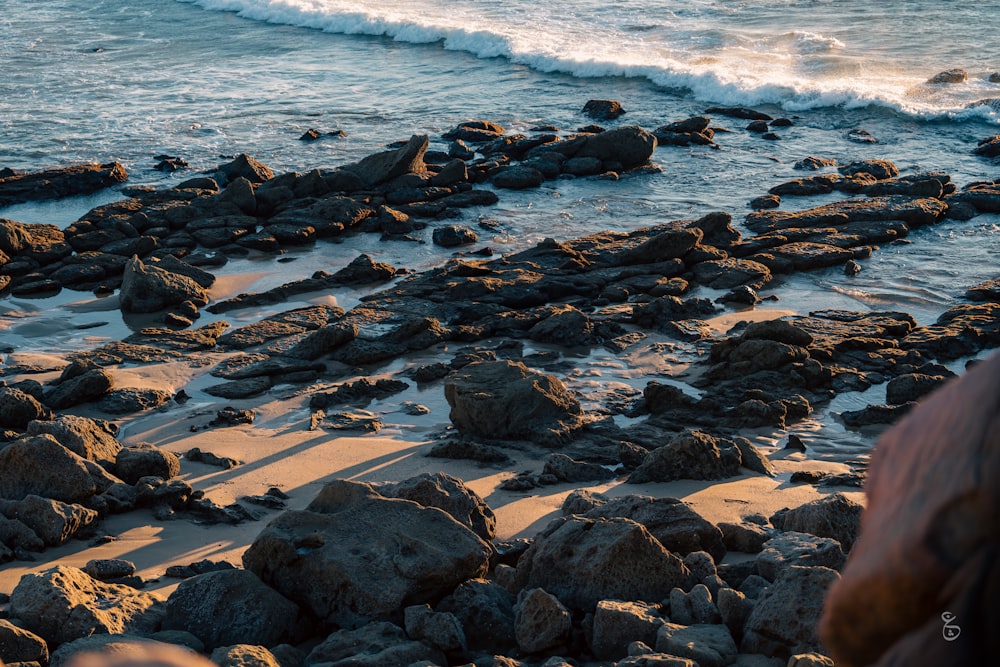 a rocky beach next to the ocean with waves coming in