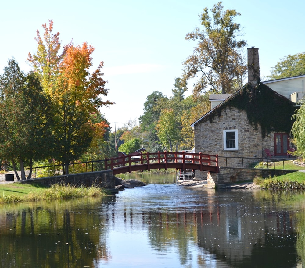 a bridge over a body of water with a house in the background