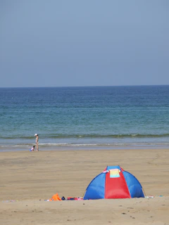A family setting up a vibrant beach tent with sand toys scattered around.
