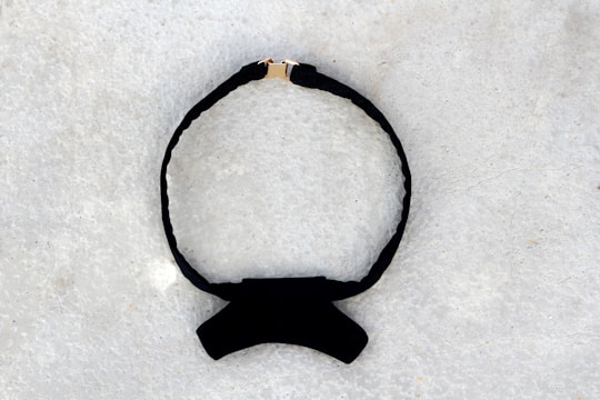 A close-up of a vintage velvet choker with subtle crimson accents against a creamy background.