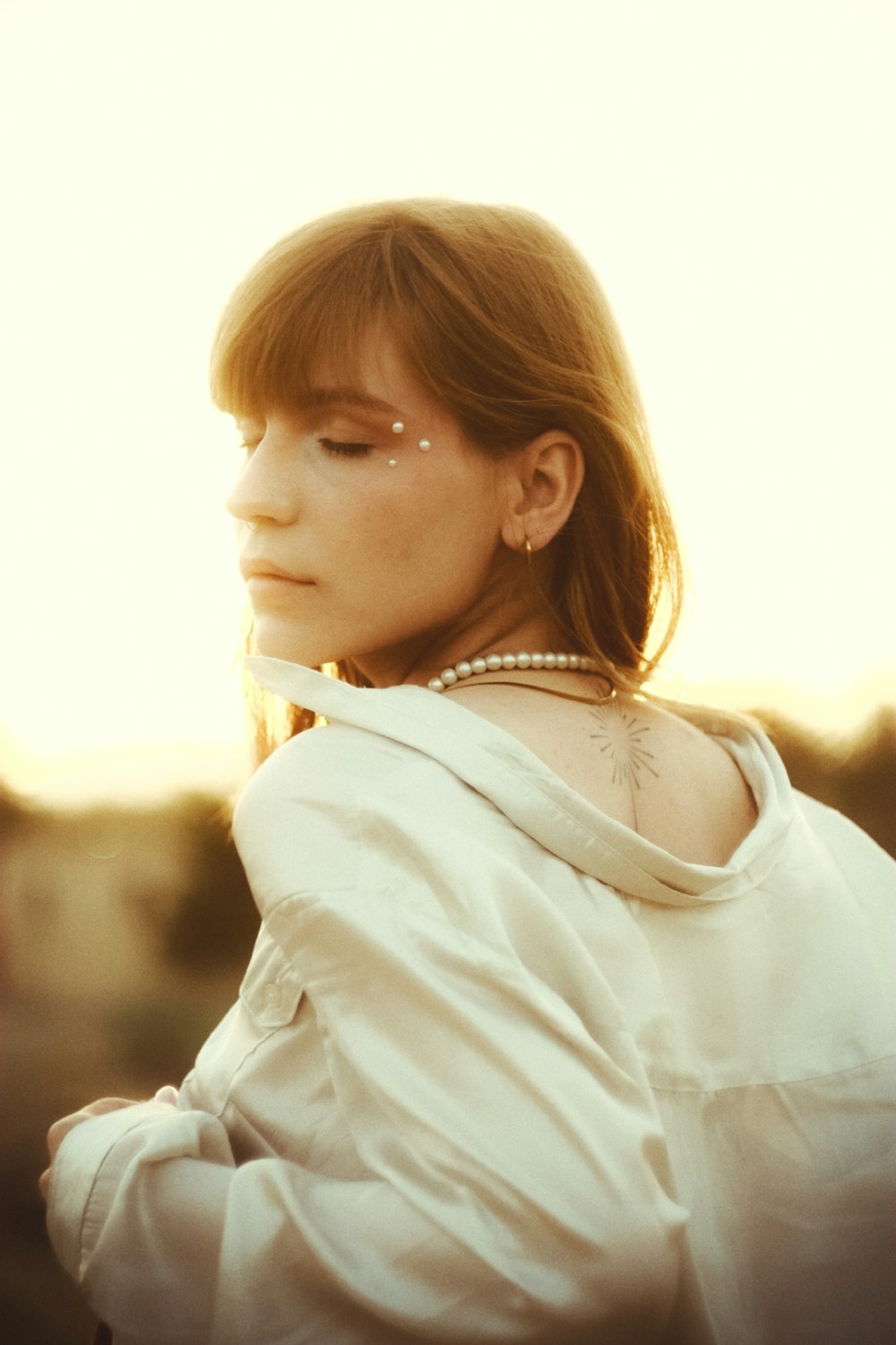a woman in a white shirt is looking off into the distance