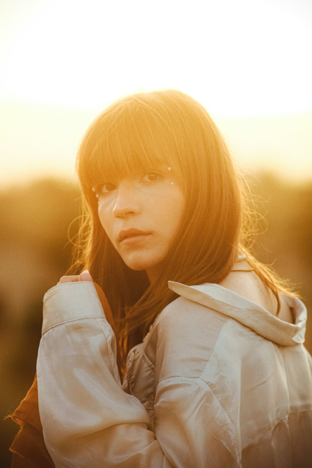 a woman standing in a field wearing a jacket