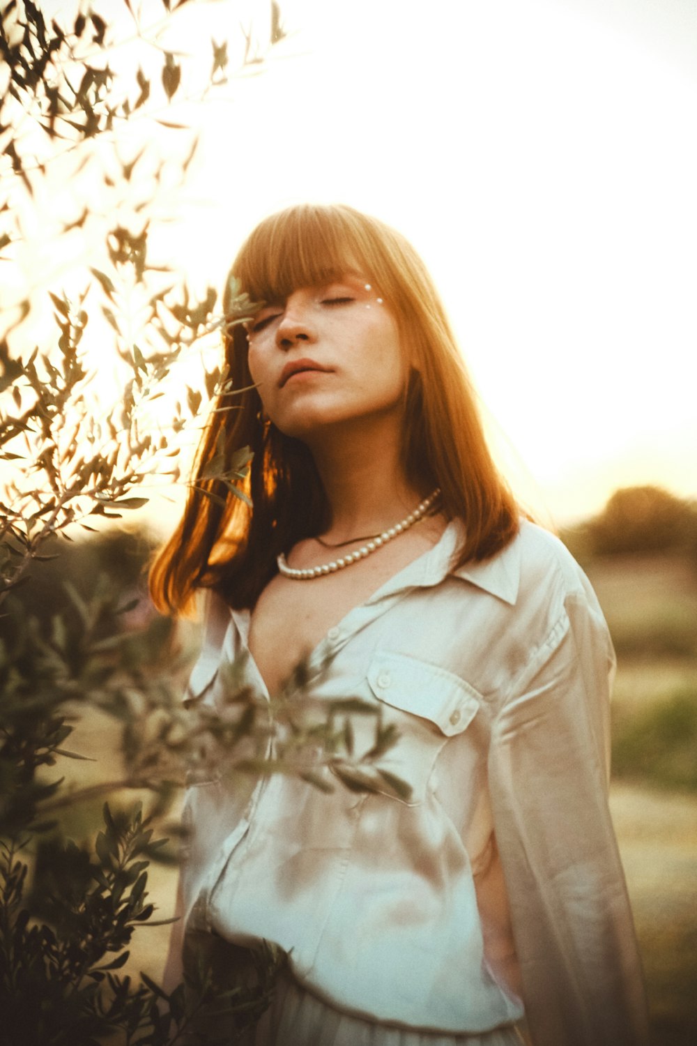 a woman standing next to a tree in a field