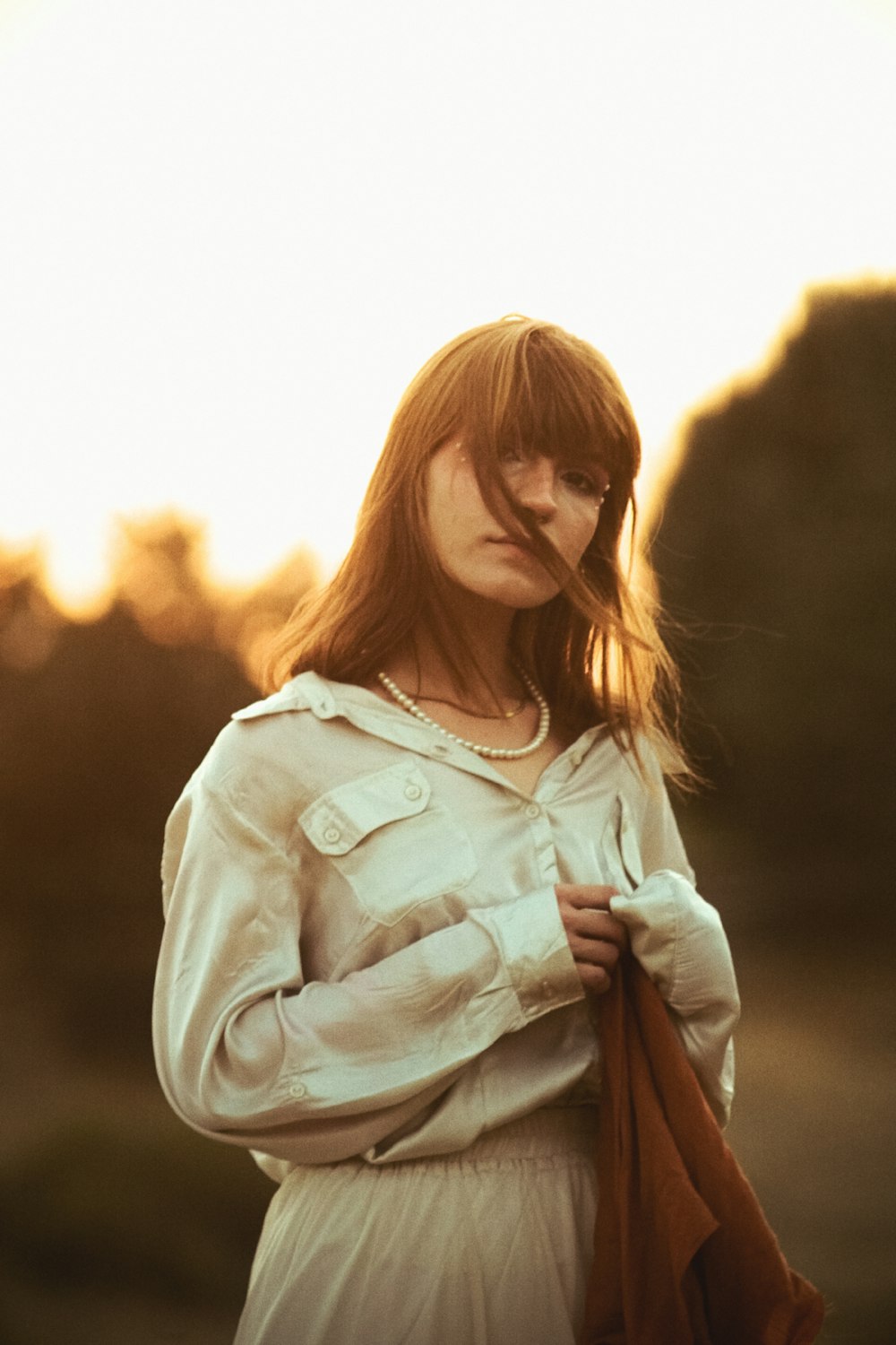 a woman in a white dress is holding a brown jacket