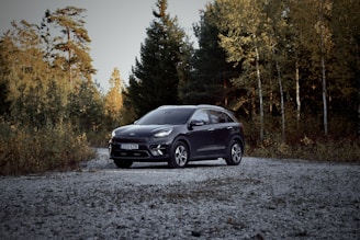 a black car is parked on a gravel road
