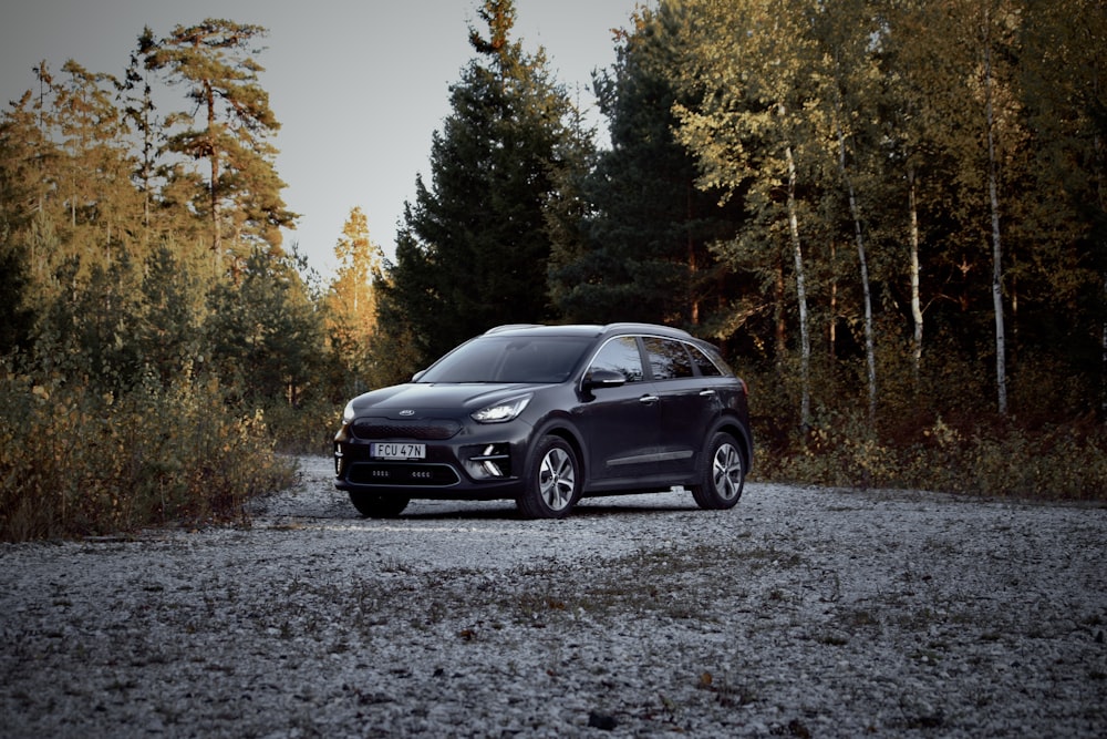 a black car is parked on a gravel road