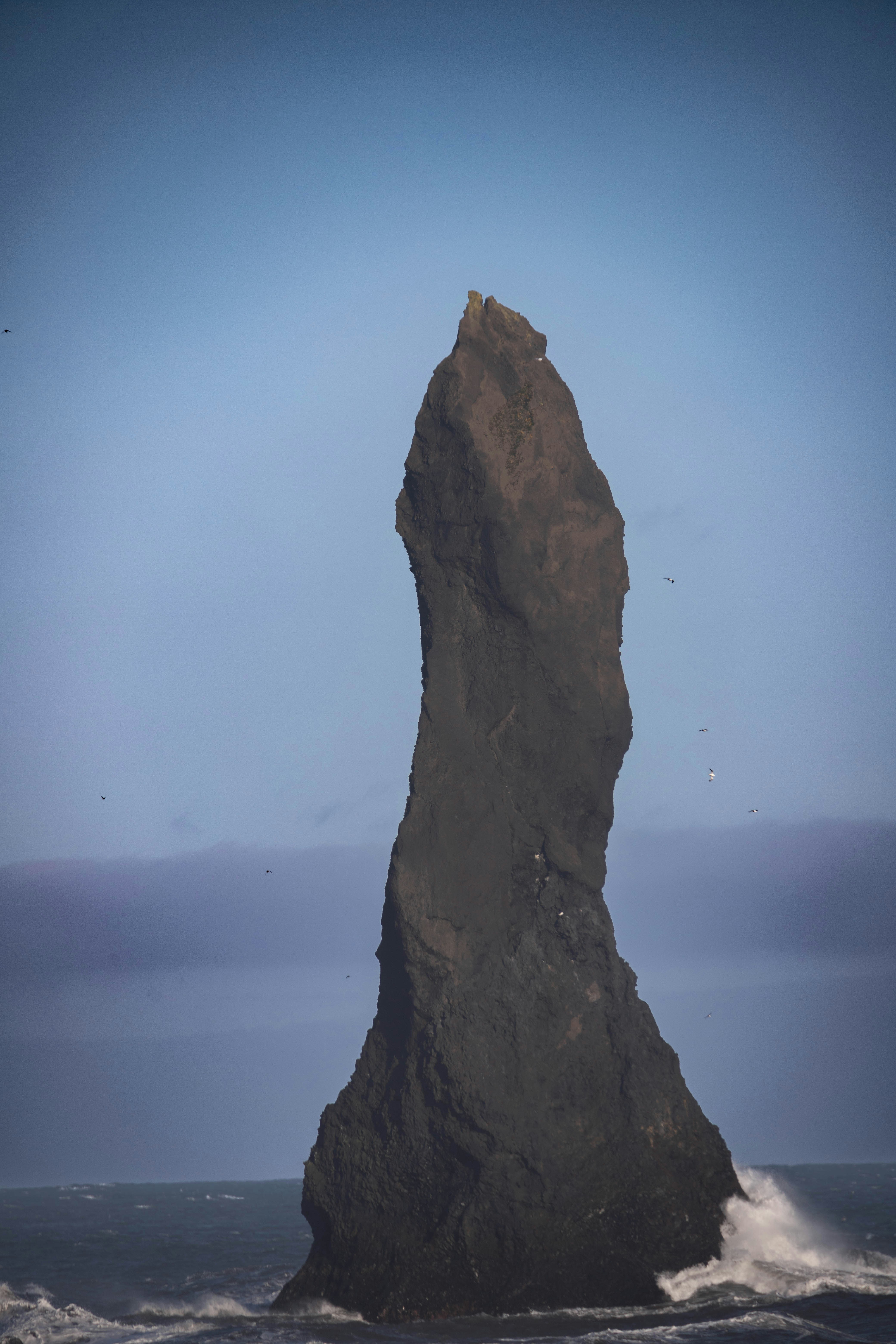 a tall rock sticking out of the ocean