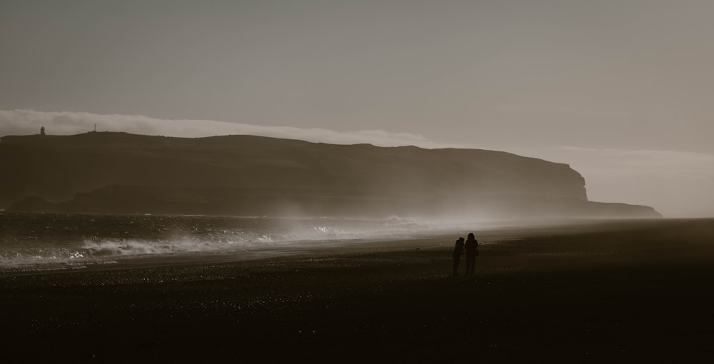 Un par de personas de pie en la cima de una playa