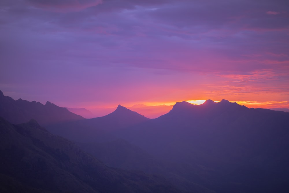 the sun is setting over a mountain range