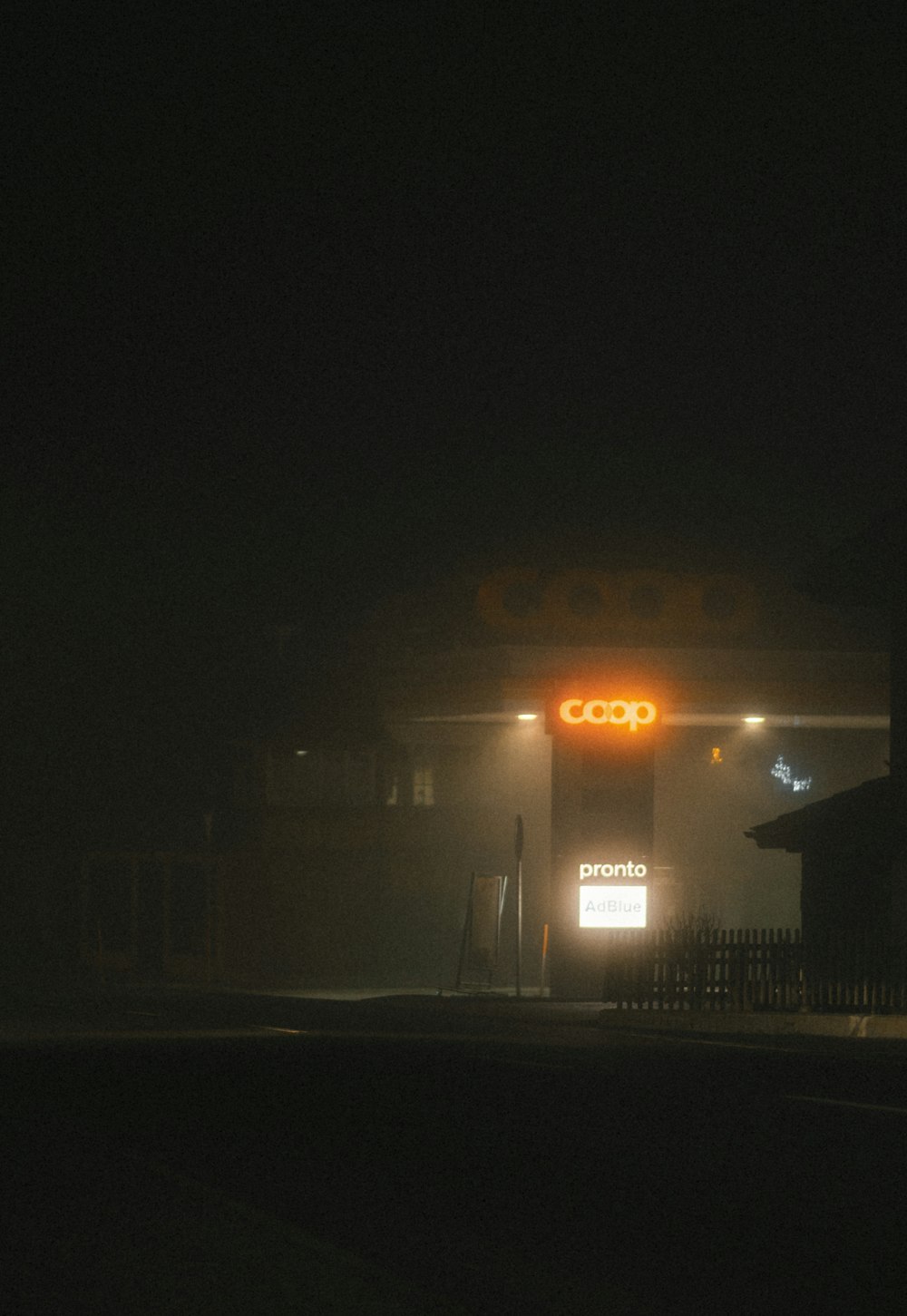a gas station at night with a foggy sky