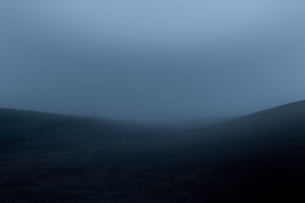 a black and white photo of a hill in the fog