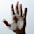 An open hand is centered against a light, neutral background while fine, dark strands are draped across the palm. The intricate pattern formed by the strands contrasts with the smooth skin.