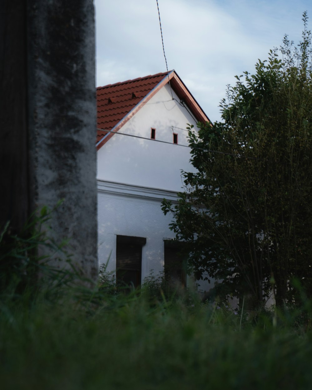 Una casa blanca con un techo rojo y un árbol