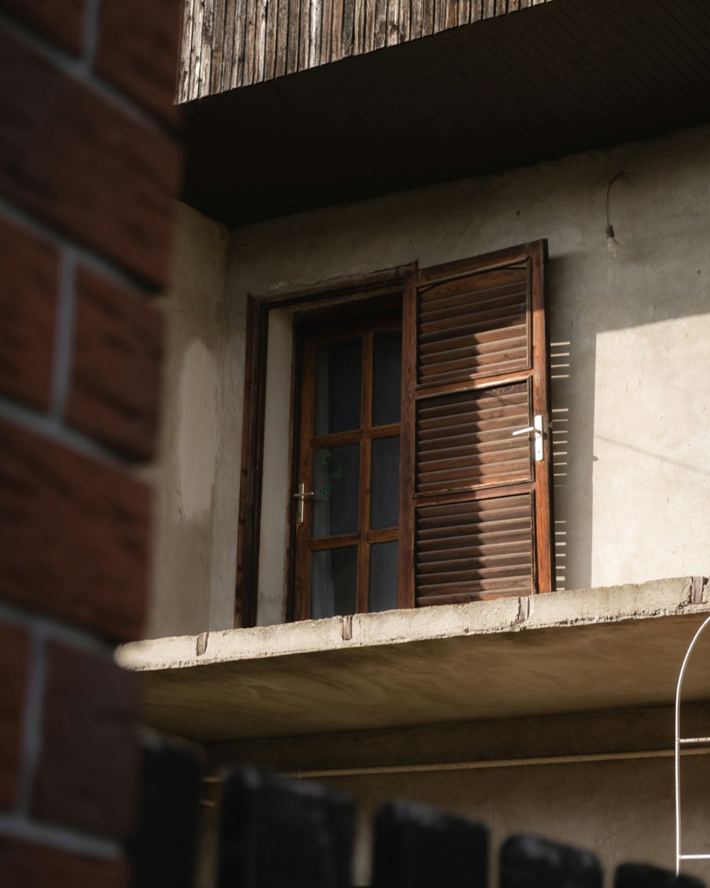 Un edificio con una ventana y un gato sentado en la cornisa