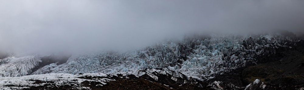 a mountain covered in snow and clouds on a cloudy day