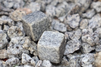 Two square-shaped granite cubes are placed on a bed of smaller irregularly shaped granite rocks, with a variety of textures and shades of gray visible.