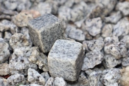 Two square-shaped granite cubes are placed on a bed of smaller irregularly shaped granite rocks, with a variety of textures and shades of gray visible.