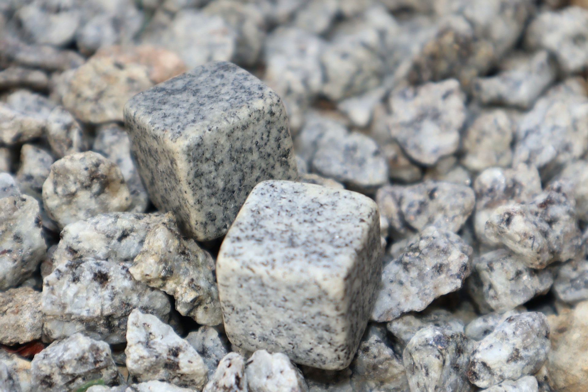 Two square-shaped granite cubes are placed on a bed of smaller irregularly shaped granite rocks, with a variety of textures and shades of gray visible.
