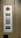 An electronic intercom system mounted on a wall, featuring a camera, a speaker, a numeric keypad, a small display screen, and a sensor for card scanning. The panel appears to be metallic with a sleek design.