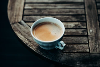 A steaming cup of dark roasted coffee on a rustic wooden table