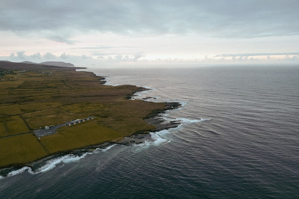 a large body of water next to a lush green field