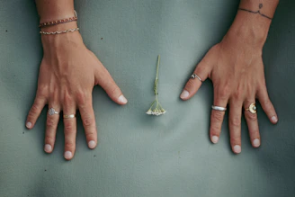 Model’s hand adorned with stackable rings, gently touching a smooth ceramic vase.
