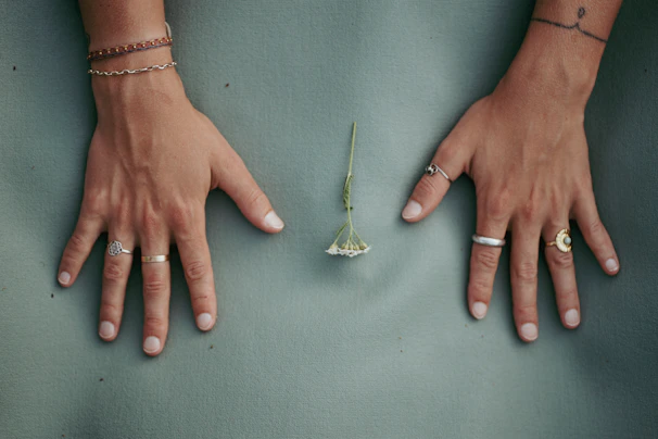 Model’s hand adorned with stackable rings, gently touching a smooth ceramic vase.
