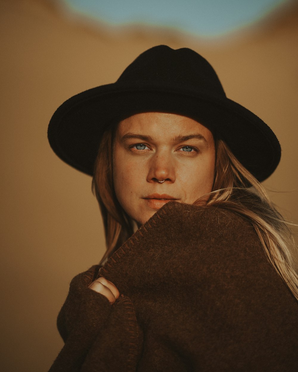 a woman wearing a black hat and a brown coat