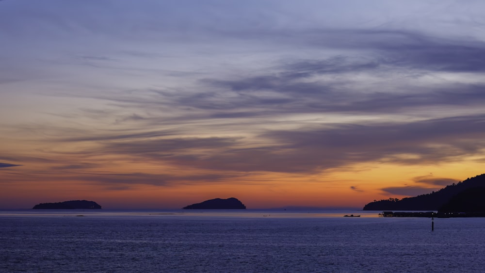 a sunset over a body of water with mountains in the background