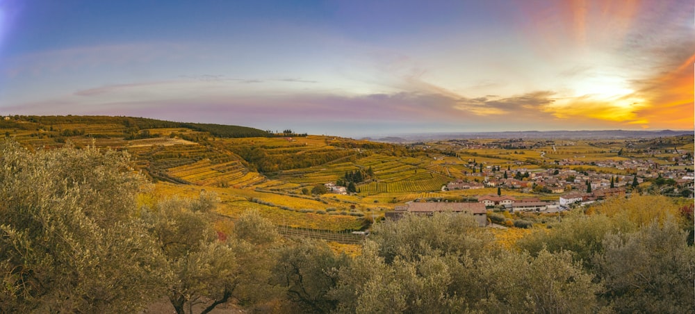 a scenic view of a valley with a sunset in the background