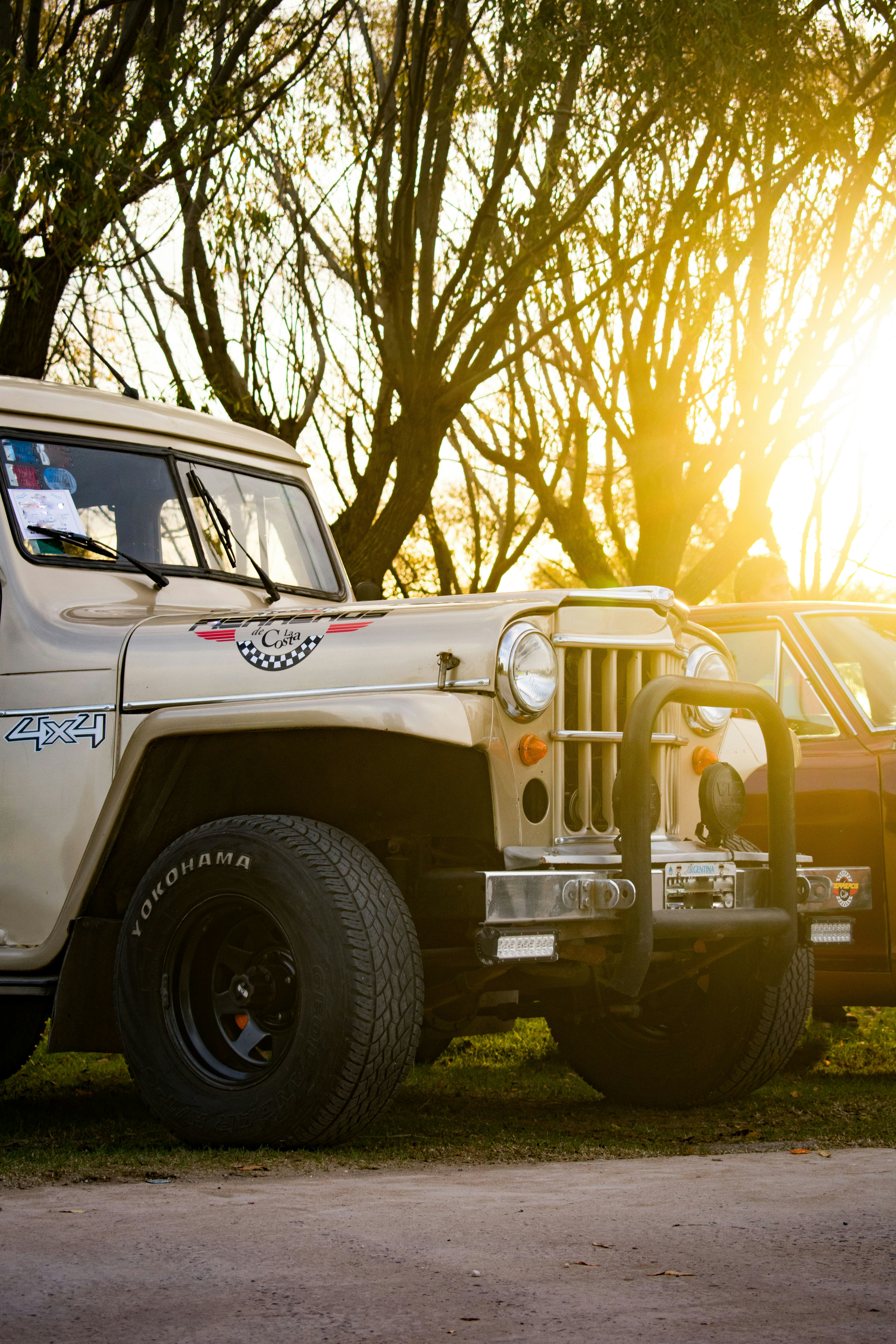 a white jeep parked in front of a tree
