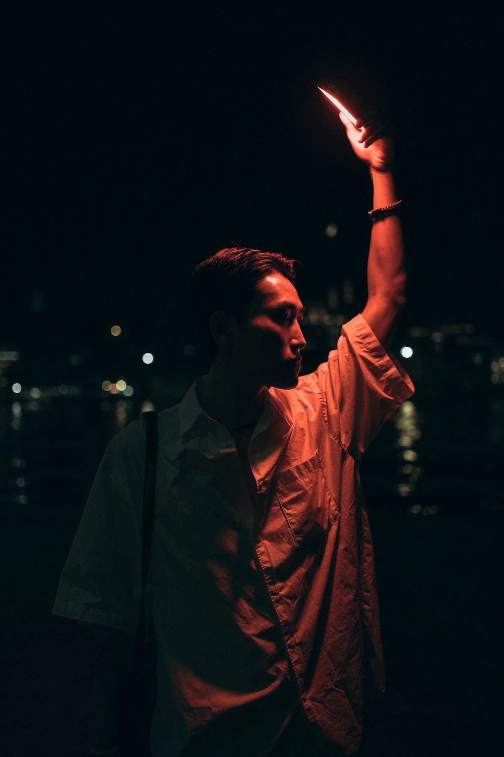 a man holding up a lit object in the dark