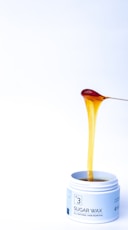a jar of sugar wax with a spoon sticking out of it