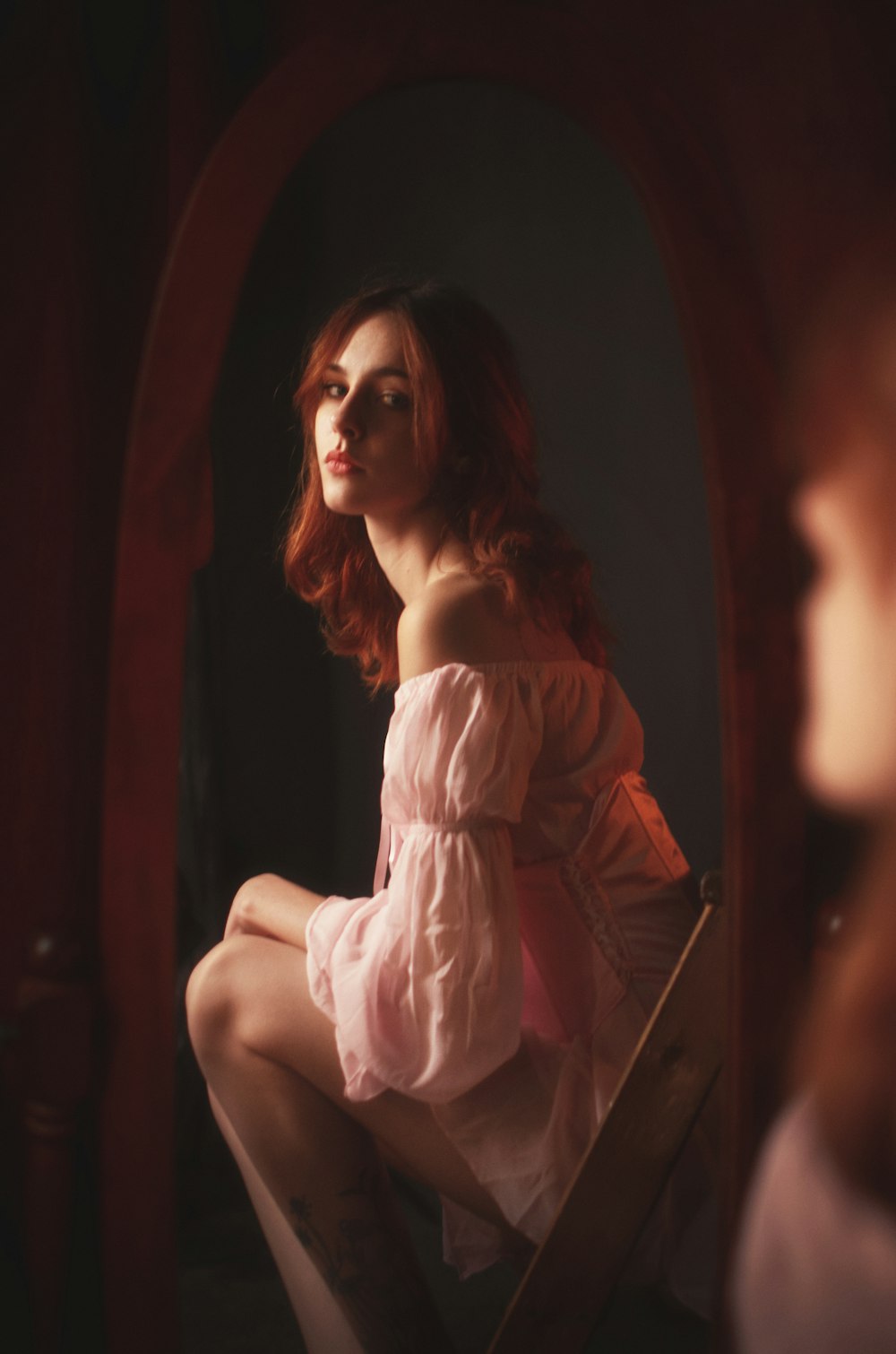 분홍색 드레스를 입은 여자가 거울 앞에 앉아 있다