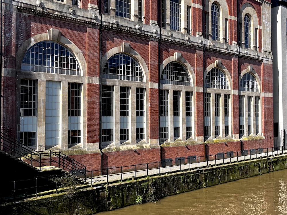 a brick building with arched windows next to a body of water