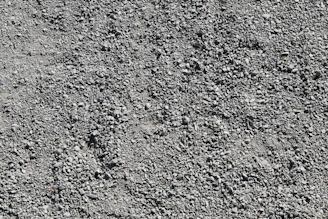 A close-up of gravel being spread evenly across a roadbed, highlighting texture and quality.